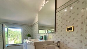 Ein modernes Badezimmer mit Waschmaschine, Waschbecken mit Spiegel und Handtuchhalter.
