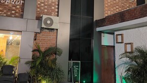 A building with a brick facade, large windows, and outdoor seating with tables and chairs. - Hotels Vibes  (Vikasnagar)