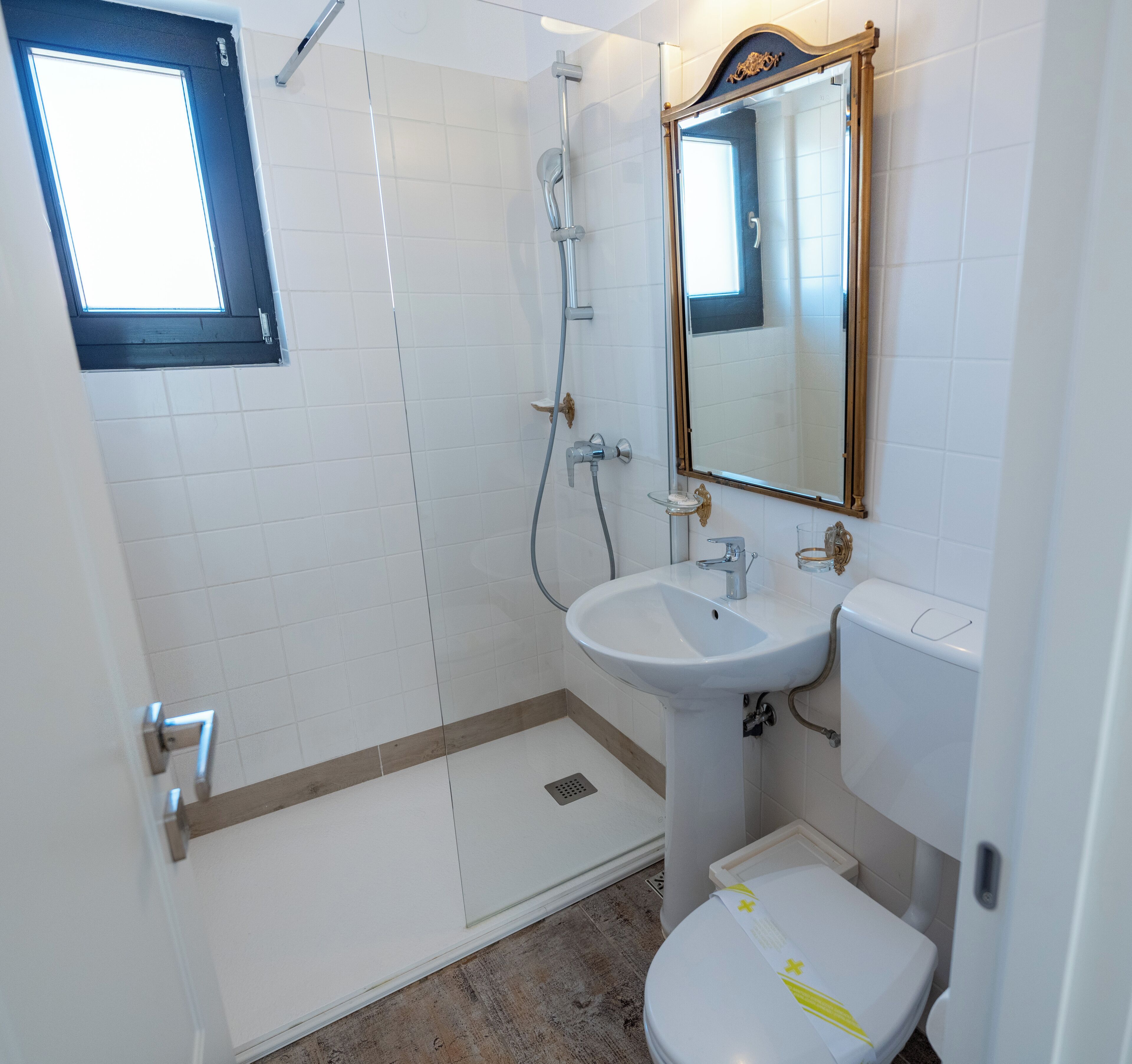 A bathroom with a shower, sink, toilet, and a mirror.