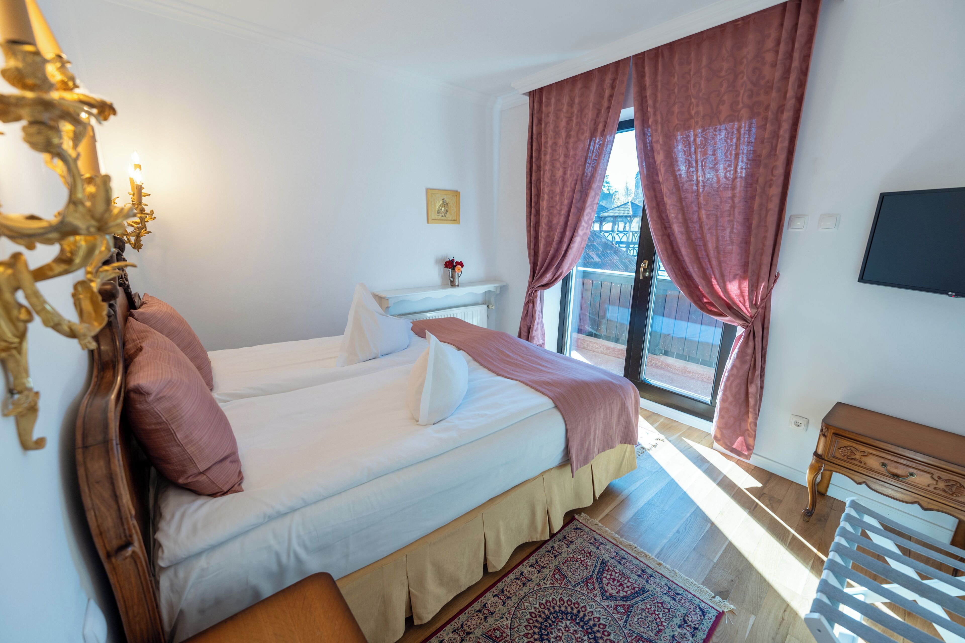 Un dormitorio con dos camas, un aparador, un televisor y una ventana con cortinas.