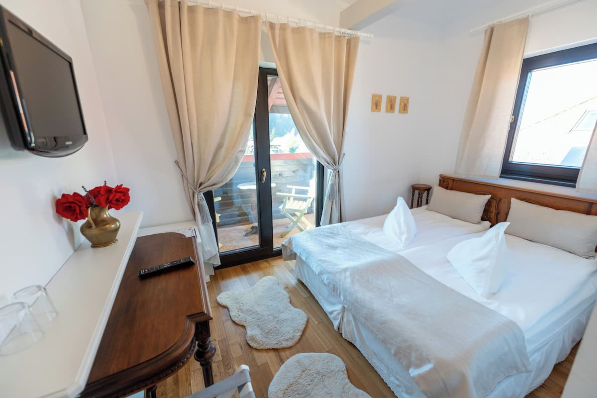 Una camera d'albergo con un letto, una televisione, una scrivania e una finestra con tende.