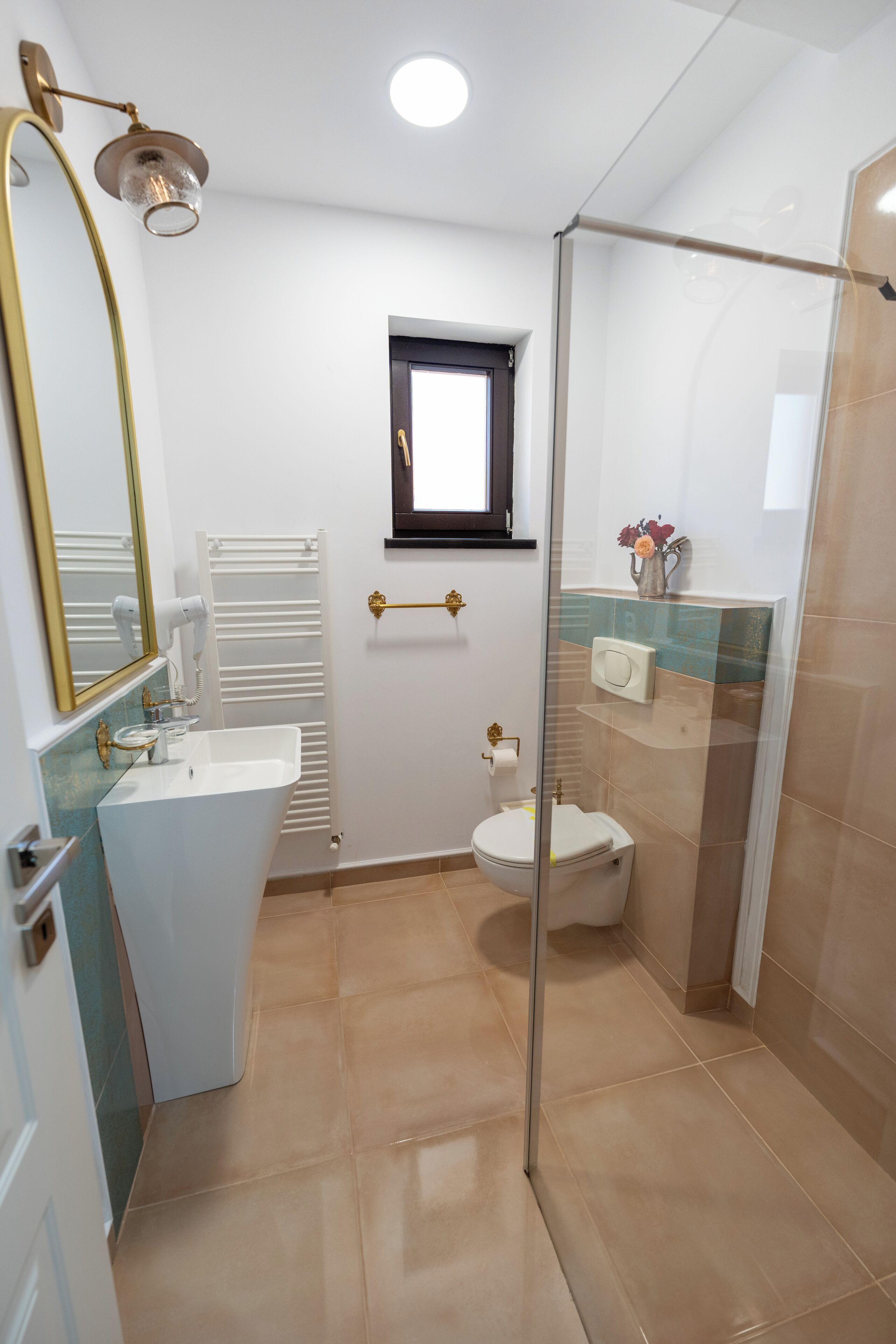 A bathroom with a glass-enclosed shower, a white sink, and a toilet.