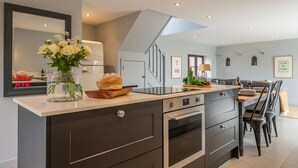 Une cuisine moderne dotée d’un îlot central, d’un four encastré et d’un coin repas avec une table et des chaises.