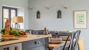 Une cuisine moderne avec un îlot central en bois, une table à manger et un panneau décoratif encadré accroché au mur.
