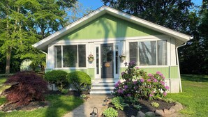 Une petite maison à un seul étage, à l’extérieur vert et blanc, avec un porche à l’avant et une boîte aux lettres portant le numéro 148.