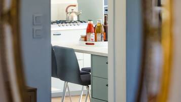Une cuisine équipée d’une cuisinière à gaz, d’une bouilloire et de diverses bouteilles posées sur le plan de travail.