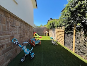 Ein Garten mit Kunstgrasanlage, einem Spielbereich und einem Holzzaun.