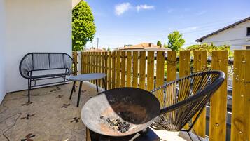 Une terrasse avec une chaise en métal, une petite table ronde et un grand wok.
