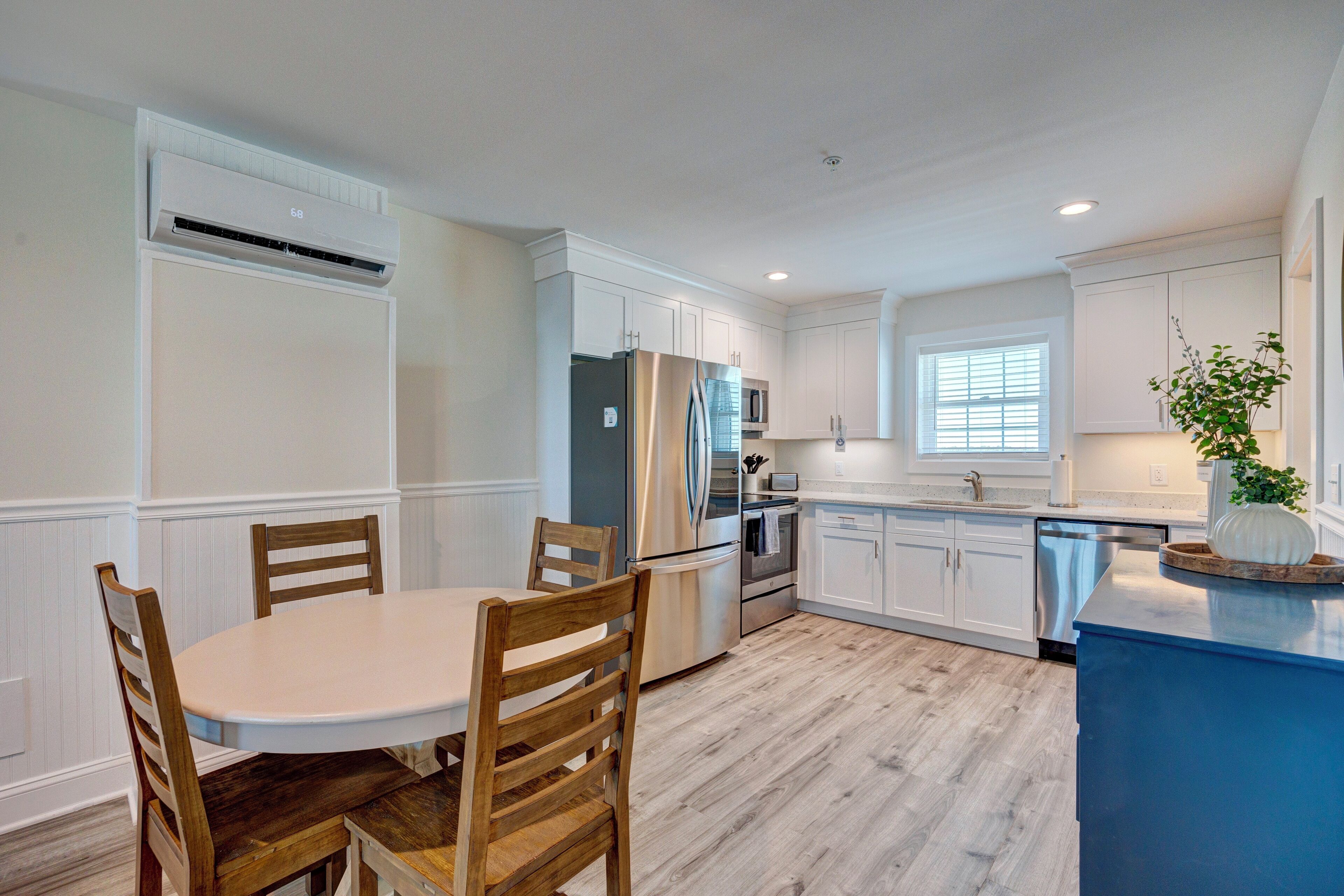 A modern kitchen with white cabinetry, a stainless steel refrigerator, and a blue island.