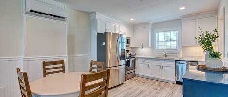 A modern kitchen with white cabinetry, a stainless steel refrigerator, and a blue island.