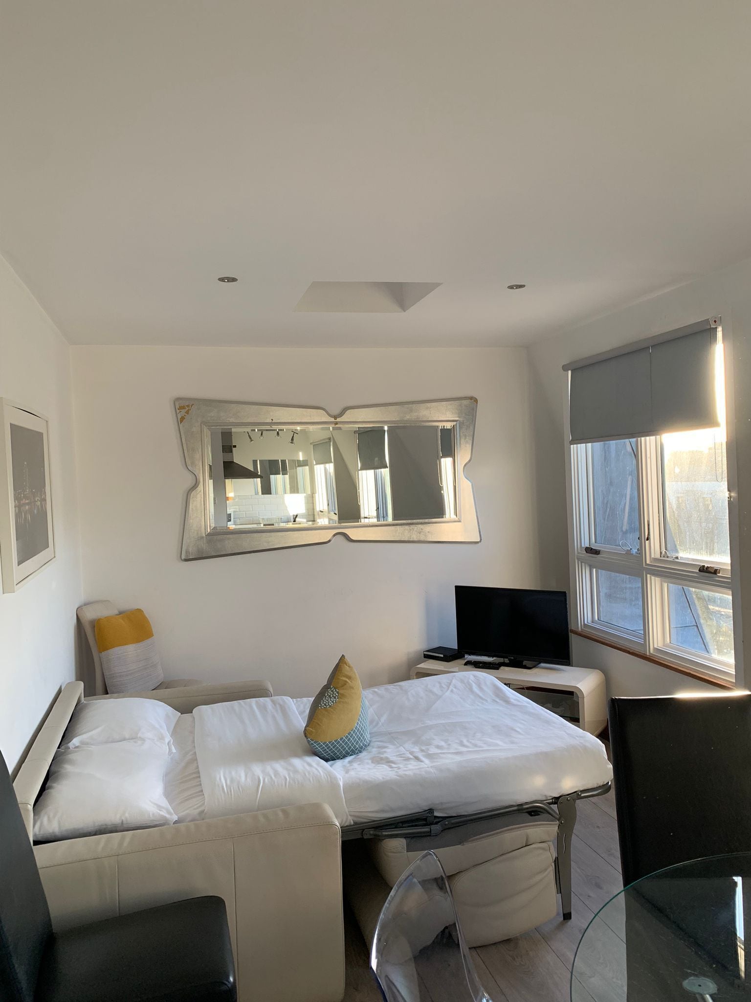 A modern hotel room with a bed, a TV, a desk, and a large window.