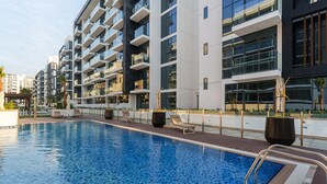A modern hotel with a swimming pool, multiple balconies, and a well-maintained outdoor area.