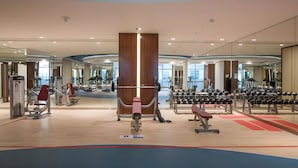 A modern gym with various exercise equipment, large mirrors, and a wooden column. - Cosmopolitan 1BR Apartment in Celestia B, Dubai South by Deluxe Holiday Homes (Dubai)