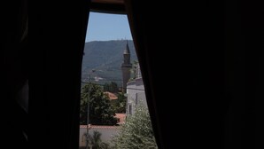 Paesaggio visto da una finestra, con una montagna e una torre all'orizzonte.