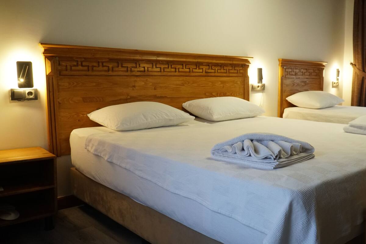 Ett hotellrum med en stor säng, två sängbord och en sänggavel i trä.