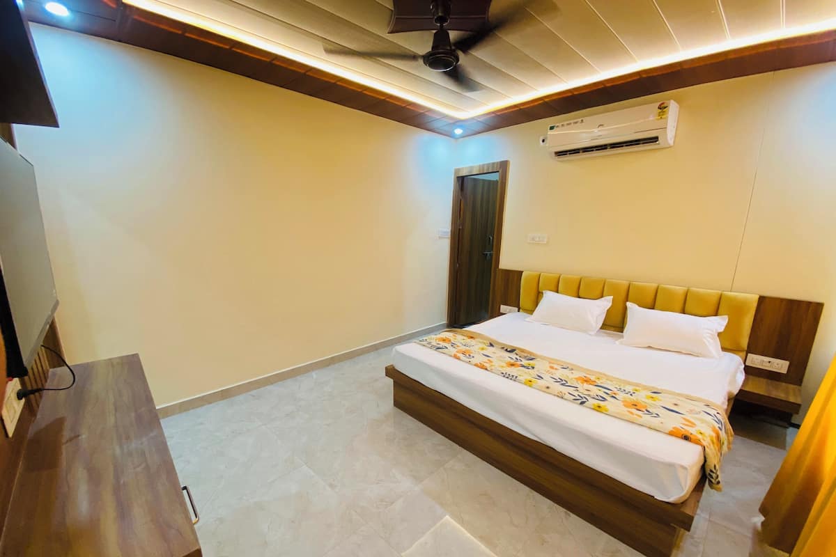 A hotel room with a bed, a desk, and an air conditioning unit.