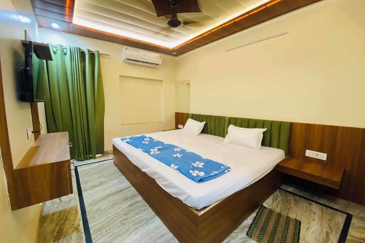A hotel room with a large bed, a flat-screen TV mounted on the wall, and a ceiling fan.