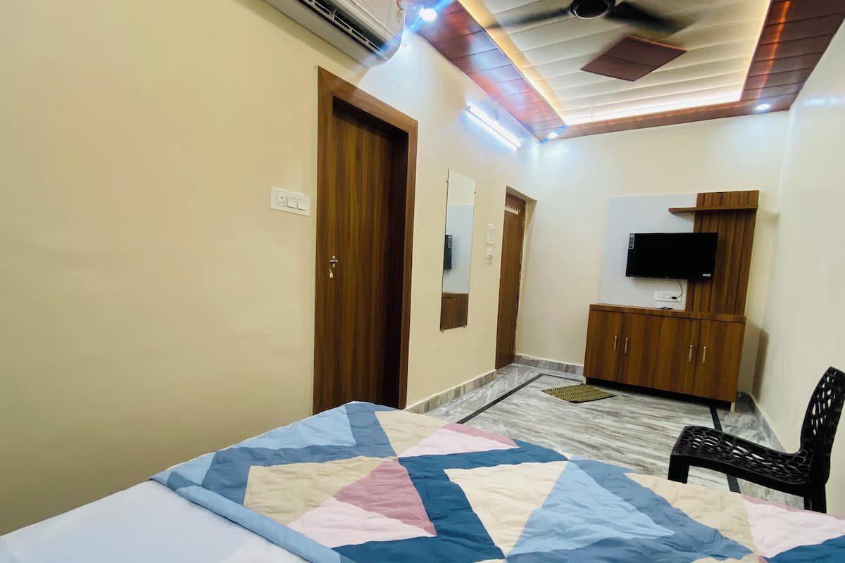 A hotel room with a bed, a wardrobe, a television, and a ceiling fan.
