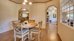 A dining area with a wooden table and chairs, a chandelier, and a view of the kitchen and living room through an archway. - Trout House, Trout House 4bd/3ba on the South Holston River (Bristol)