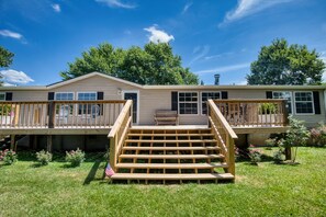 A two-story mobile home with a wooden deck, a front porch, and a small garden. - Trout House, Trout House 4bd/3ba on the South Holston River (Bristol)