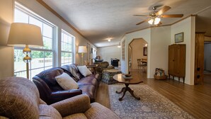 A spacious living room with a leather sofa, a wooden coffee table, and a large window providing natural light. - Trout House, Trout House 4bd/3ba on the South Holston River (Bristol)