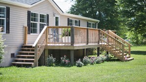 A two-story house with a wooden deck and stairs leading to a front door. - Trout House, Trout House 4bd/3ba on the South Holston River (Bristol)