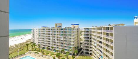 Un hotel moderno de gran altura con varios balcones, piscina y vista a la playa.