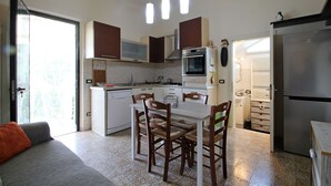 A compact kitchen with white cabinets, a built-in oven, and a dining area with a table and chairs.