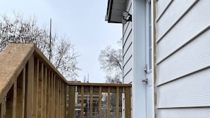 Um deck de madeira com vista para uma casa ao fundo.