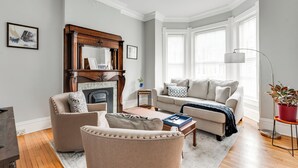 A living room with a fireplace, a sofa, a coffee table, and a floor lamp. - Charming 2-bedroom house with WiFi, AC, & Patio in the heart of Richmond! (Richmond)