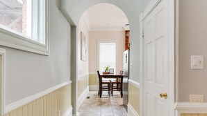 A hallway with a dining table and chairs, a white door, and a window. - Charming 2-bedroom house with WiFi, AC, & Patio in the heart of Richmond! (Richmond)