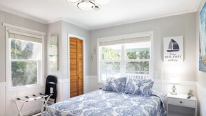 Ein Schlafzimmer mit Bett, Nachttisch, Lampe und einem Sessel.