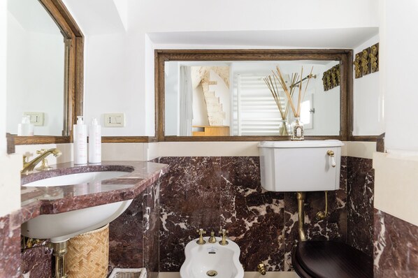 A bathroom with a marble sink, a white toilet, and a large mirror. - Terrazza Olivia Maria by Wonderful Italy (Ostuni)
