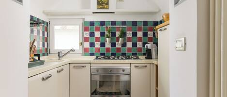 A compact kitchen with a tiled backsplash, a built-in oven, and a gas stove.