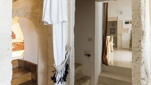 Interior de paredes de piedra con una escalera que sube a un segundo piso.