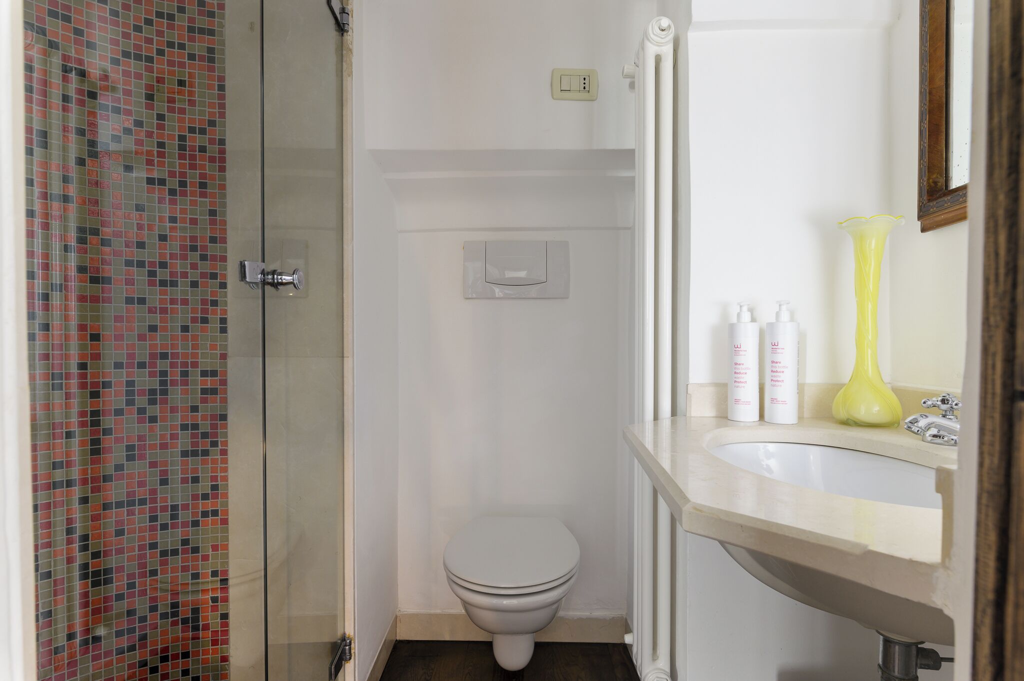 A bathroom with a shower, toilet, sink, and a mirror.