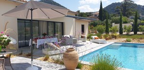 A poolside area with a dining setup, outdoor furniture, and a large vase. - Villa Provençale Contemporaine Avec spa (Seguret)