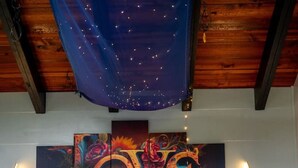 A bedroom with a bed, colorful artwork, and wall-mounted lights.