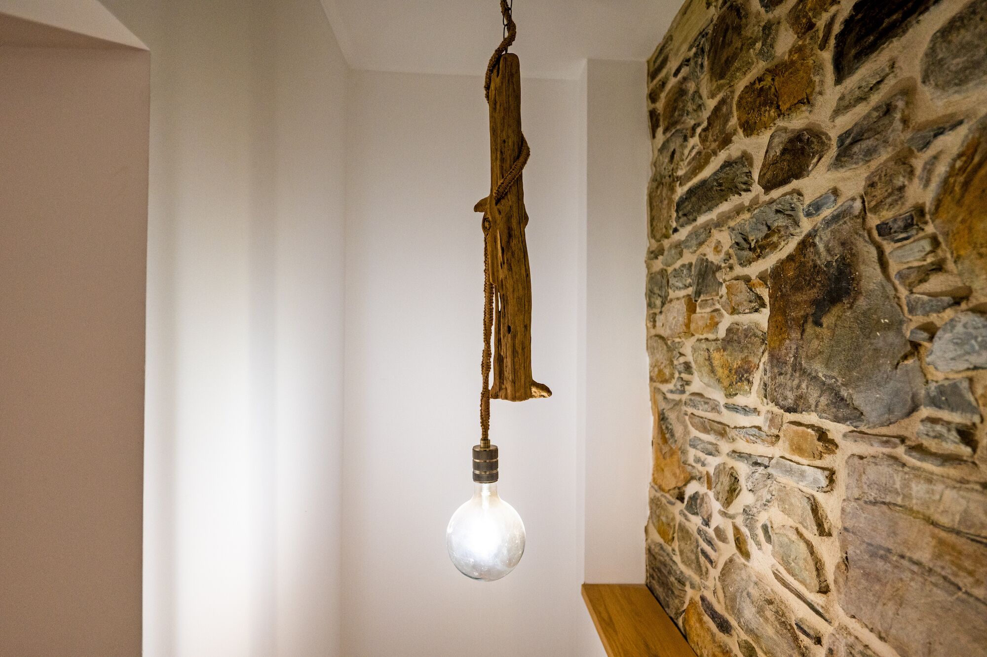 A rustic interior with a hanging light fixture and a stone wall.