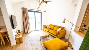 Un salon moderne avec un canapé jaune, une petite table ronde et un lampadaire.