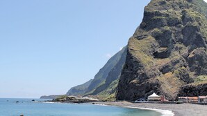 Un hôtel situé sur la côte, avec une falaise imposante, un accès direct à la plage et un ciel dégagé.