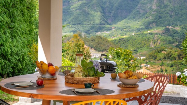 Une table ronde en bois, dressée pour le petit-déjeuner, avec vue sur un paysage montagneux.