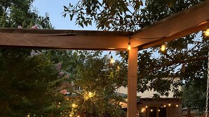 Ein überdachter Außenbereich mit Pool, einer Pergola mit Lichterketten und einem Volleyballnetz.
