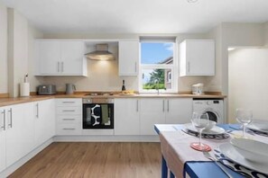 Eine moderne Küche mit weißen Schränken, einer Holz Arbeitsplatte und einem eingebauten Backofen.