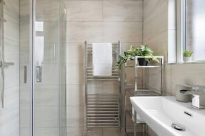 A modern bathroom with a glass shower enclosure, a towel rack, and a sink with a mirror.