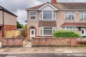 A two-story residential house with a brick facade, a front door, and a small front garden.