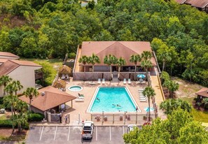 A hotel with a swimming pool, lounge chairs, and palm trees.