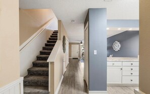 Un pasillo con una escalera alfombrada que conduce a una habitación con una puerta blanca.