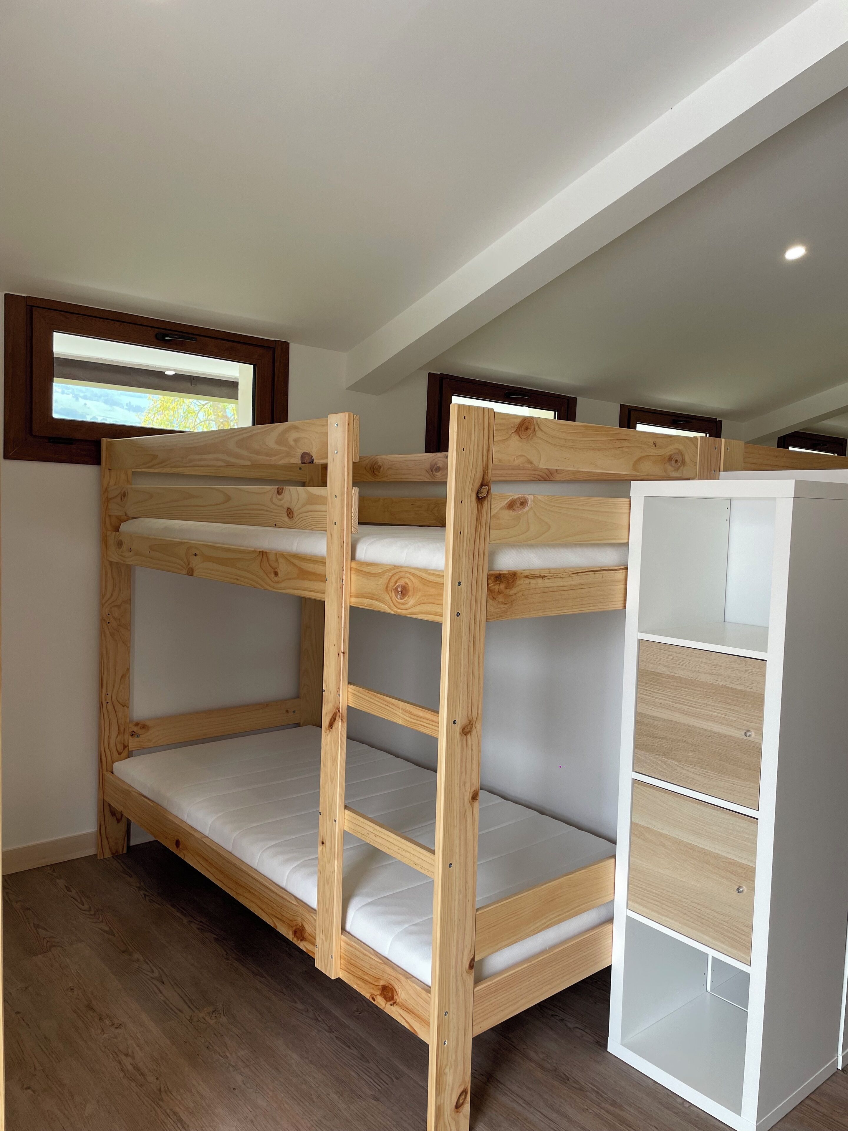 A bunk bed with a white storage unit beside it.
