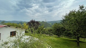 A house with a red roof, surrounded by lush greenery and a view of rolling hills. - Larraitz Aterpetxea (PV)